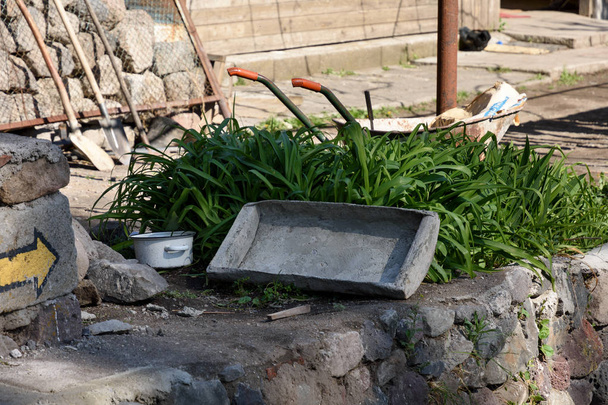 Старий корито, що використовується для розведення бетону, лежить в траві біля будинку. Село хутвіці - Фото, зображення