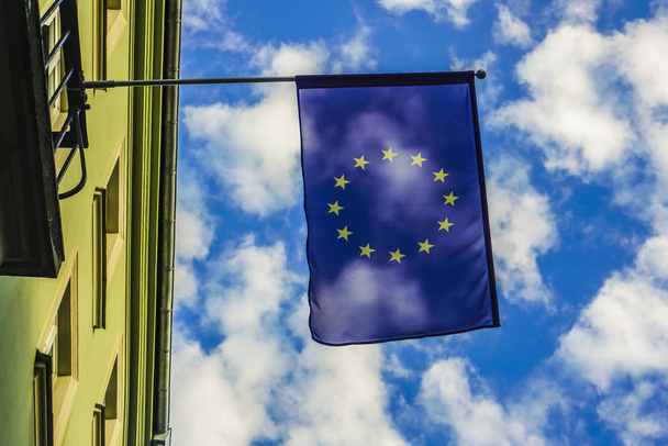 Flag of the European Union waving in the wind on flagpole against blue sky on sunny day, close-up - Foto, Imagem