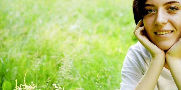 Beautiful portrait of pensive young short haired girl on blurred green grass meadow background, closeup.  - Foto, immagini