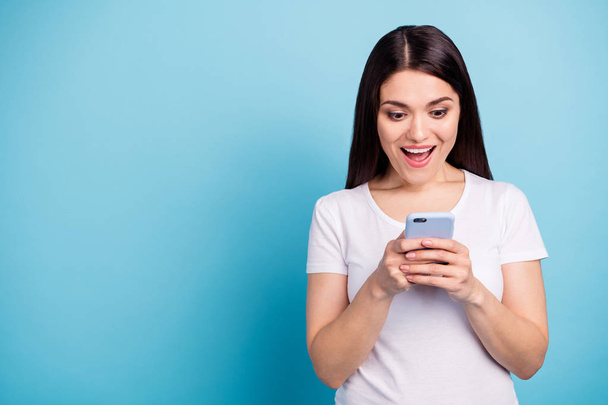 Фотография симпатичной симпатичной веселой девушки, которая видит информацию о продажах на своем телефоне, находясь в изоляции на синем фоне
 - Фото, изображение
