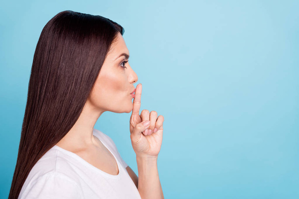 Close up copyspace photo of charming cute woman showing point finger on her lips for all to keep silent while isolated with blue background - 写真・画像