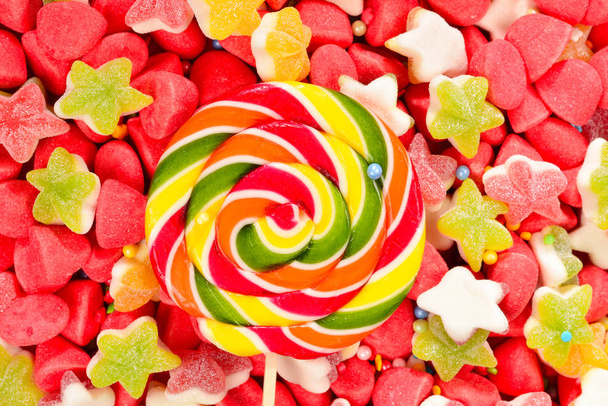 Assortiment de bonbons gommeux colorés et sucette sur fond rouge
.  - Photo, image