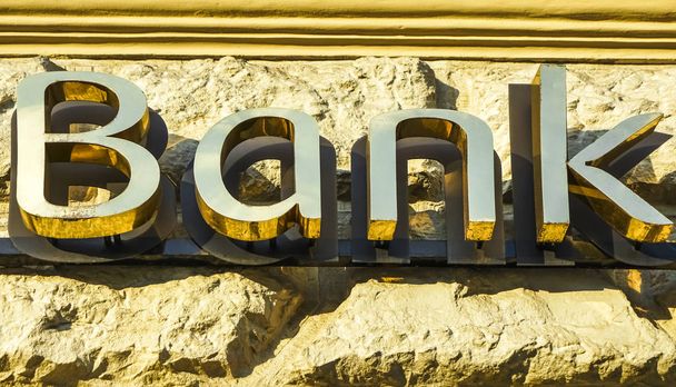 Old fashioned bank sign with ornamental wrought iron and golden letters. Building exterior of a bank. Finance symbol.  - Foto, Imagen