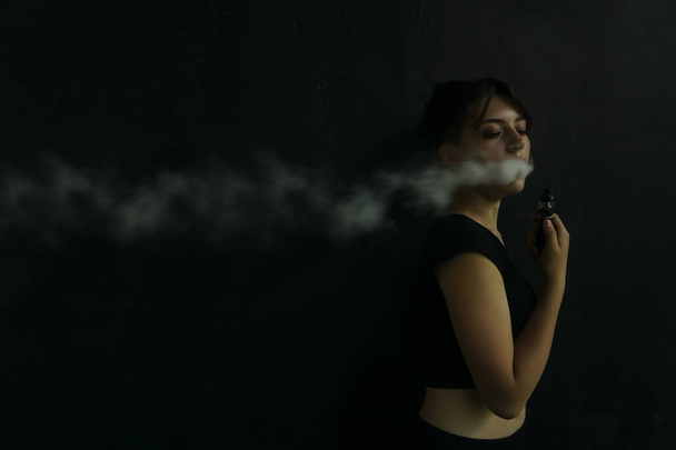 Vape Party. Beautiful Sexy Young Woman with glamorous mystical makeup vaping in Nightclub (exhaling smoke).  - Photo, image