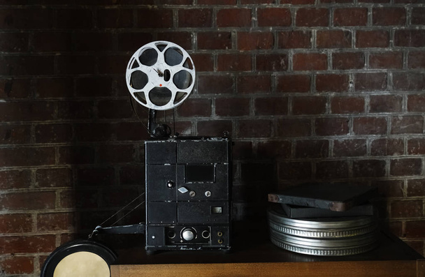 photo of an old movie projector on brick wall background. Old style movie projector, still-life, close-up. - Foto, Imagen