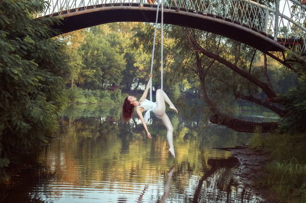 Porträt der Akrobatin auf Leinwänden über dem Fluss. - Foto, Bild