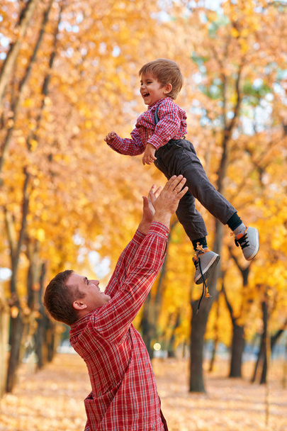 Gelukkige familie met vakantie in de herfst stadspark. Kinderen en ouders die poseren, glimlachen, spelen en plezier hebben. Heldere gele bomen en bladeren - Foto, afbeelding