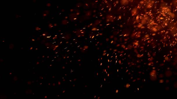 Chispas rojas ardientes vuelan desde un gran fuego en el cielo nocturno. Hermoso fondo abstracto sobre el tema de fuego, luz y vida. Brasas ardientes que brillan volando lejos partículas sobre fondo negro. - Foto, Imagen
