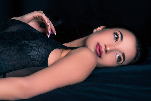 Pretty woman lying on black sheets - Valokuva, kuva