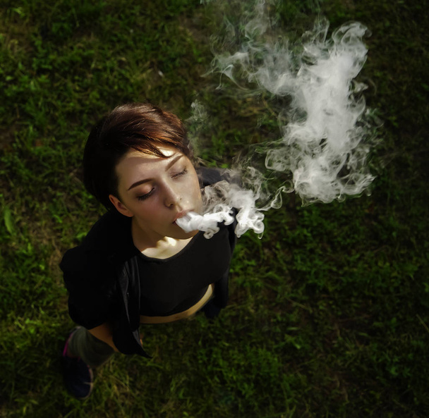 young girl smokes electronic cigarette - Фото, зображення