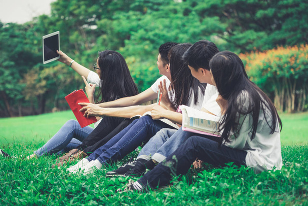Ομάδα νεαρών φοιτητών που σπουδάζουν στο πάρκο. - Φωτογραφία, εικόνα
