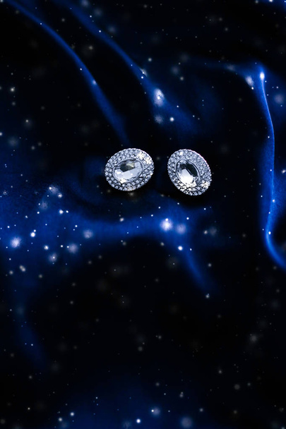 Luxe diamanten oorbellen op donker blauwe zijde met sneeuw glitter, hol - Foto, afbeelding