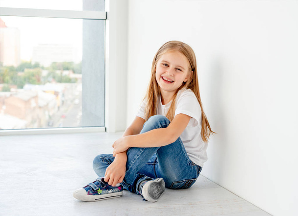 Smiling little girl sitting on the floor - Foto, Imagen