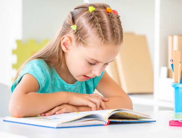 Cute schoolgirl reading book, closeup - Fotó, kép