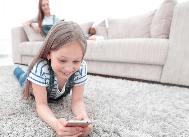 mom and her daughter using their smartphones in the spacious living room - Photo, image
