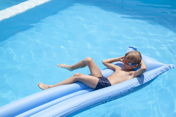 a boy is swimming on a mattress in the pool in the Villa - Foto, afbeelding