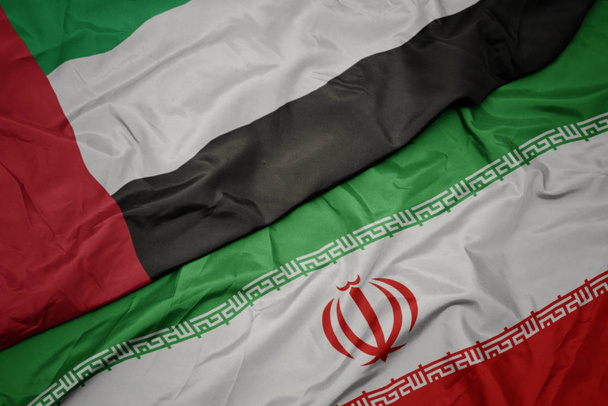 ondeando colorida bandera de Irán y bandera nacional de emiratos árabes unidos
. - Foto, Imagen