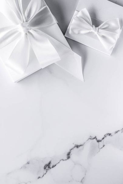 Роскошные свадебные подарки с шелковым луком и лентами на мраморной спине
 - Фото, изображение