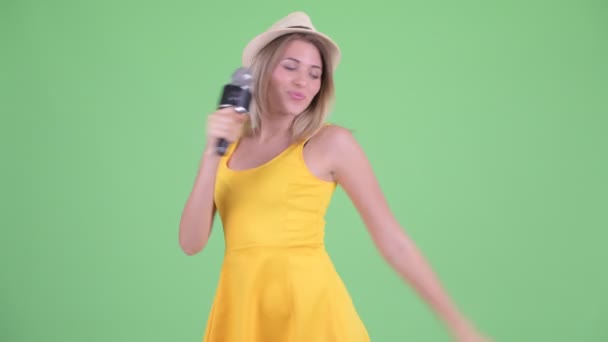 Happy young blonde tourist woman singing with microphone - Imágenes, Vídeo