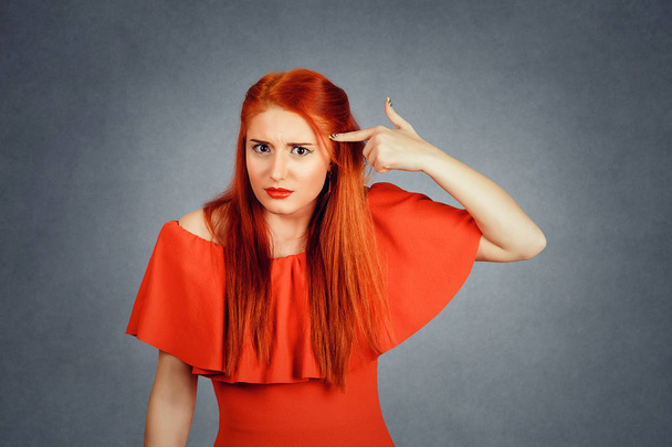 Woman on red background looks at her head. - Photo, Image