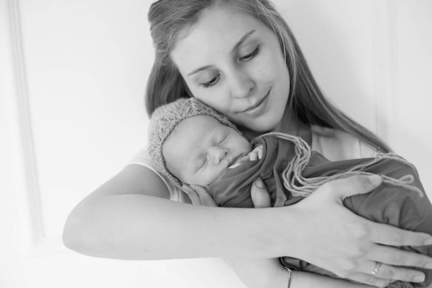 A lovely young mother holds a sleeping newborn baby in her arms. The concept of family and healthy motherhood - Fotoğraf, Görsel