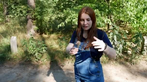 青いオーバーオールの女の子は、夏の森を歩きます - 映像、動画