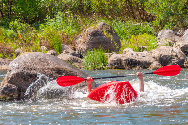 La navigation de plaisance. Un homme assis dans un kayak avec des rames à la main effectue des exercices sur l'eau. Kayak freestyle en eau vive. Rouleau esquimau
. - Photo, image
