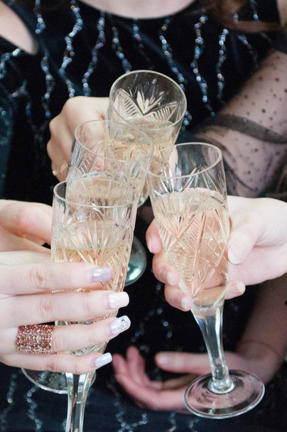 Festive glasses with champagne in female hands. Christmas celebration, birthday, hen party, wedding - Photo, Image