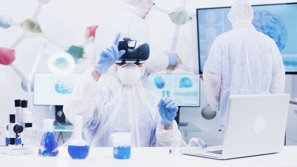 Femme scientifique avec casque de réalité virtuelle dans un laboratoire de chimie moderne
 - Séquence, vidéo