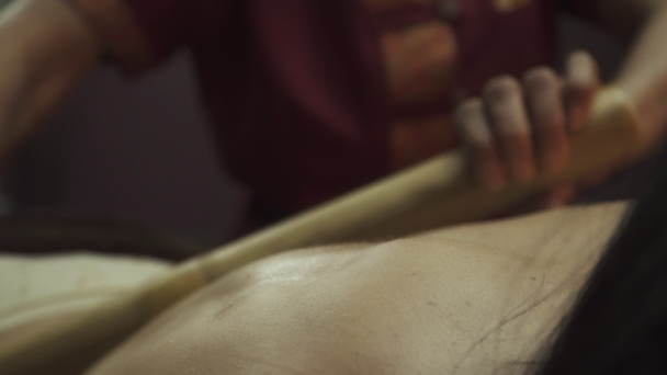 Mujer joven acostada en la cama de madera spa tienen palos de terapia de masaje corporal de bambú. Primer plano
. - Imágenes, Vídeo