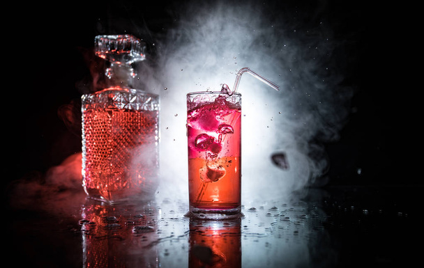 Bicchiere da cocktail spruzzato su sfondo fumé scuro o cocktail colorato in vetro. Intrattenimento da party club. Luce mista
. - Foto, immagini