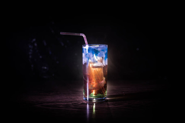 Cocktail vidro espirrando sobre fundo fumado tonificado escuro ou coquetel colorido em vidro. Entretenimento do clube de festas. Luz mista
. - Foto, Imagem