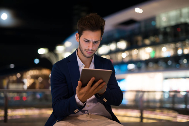 Portrait of man using his tablet in a city at night - Foto, Bild