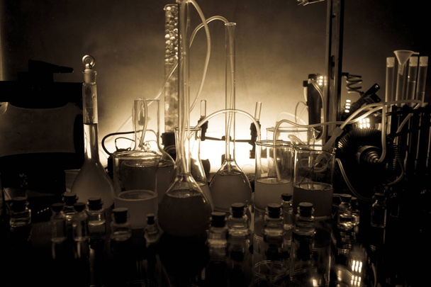 Pharmacy and chemistry theme. Test glass flask with solution in research laboratory. Science and medical background. Laboratory test tubes on dark toned background - Photo, Image