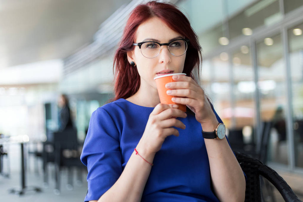 pensive woman thinking, holding takeaway cup in a coffee shop terrace in the street - Photo, image