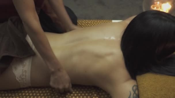 Masseuse palms massages the back of a beautiful girl. The candles burn in the corner. Close-up. - Metraje, vídeo