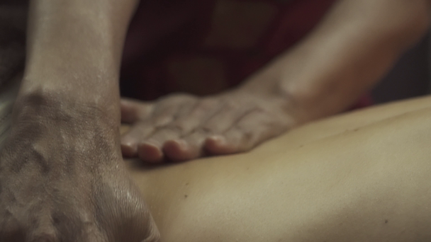 Klient masáže má záda a ramena olejem. Masérka se dotýká chlapecké kůže. Lázeňský klient, který dostává velkou thajskou masáž. Detailní záběr. - Záběry, video