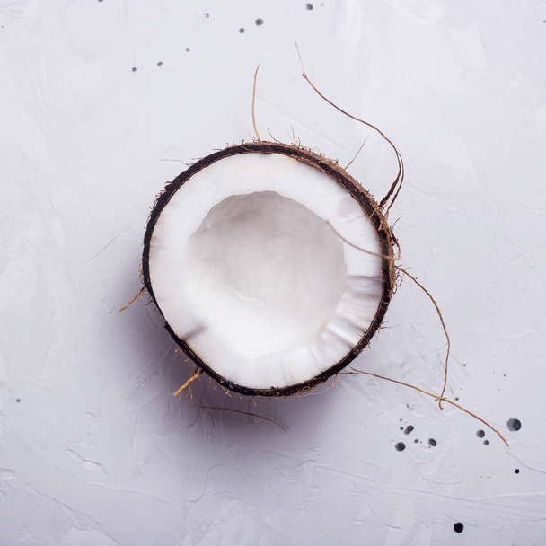 Half a coconut in shell on a gray concrete background - Zdjęcie, obraz