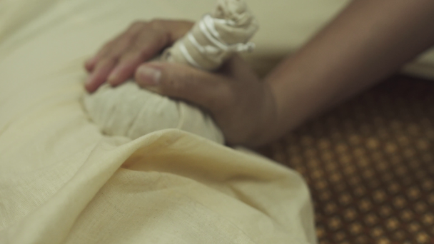 Thajská masáž bylinkovými sáčky. Pohledný muž se dobře baví na masážním lůžku. Detailní záběr. - Záběry, video