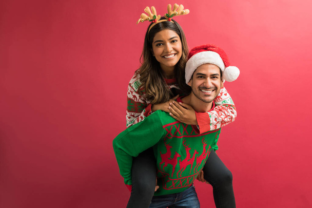 Iloinen poikaystävä antaa reppuselässä tyttöystävä joulun aikana juhla vastaan tavallinen tausta
 - Valokuva, kuva