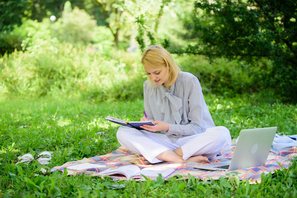 Girl with notepad write note. Freelance career concept. Guide starting freelance career. Business lady freelance work outdoors. Become successful freelancer. Woman with laptop sit on rug grass meadow - Фото, зображення