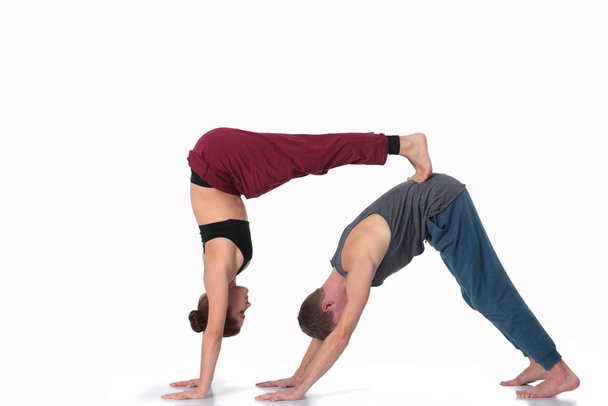 Young athletic couple practicing acroyoga. Balancing in pair. - Фото, изображение