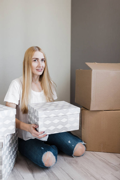 mortgage, people and real estate concept - happy woman with boxes moving to new home - Zdjęcie, obraz