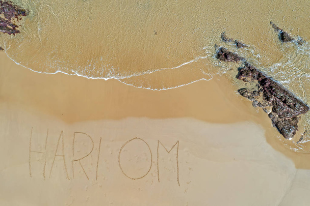 Aerial top shot from ocean waves and handwritten Hari Om at the  - Photo, Image