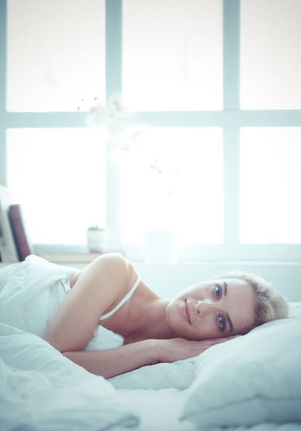 Pretty woman lying down on her bed at home - Fotoğraf, Görsel