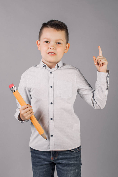 αγόρι κρατά ένα μεγάλο μολύβι, την έννοια του σχολείου, την εκπαίδευση - Φωτογραφία, εικόνα