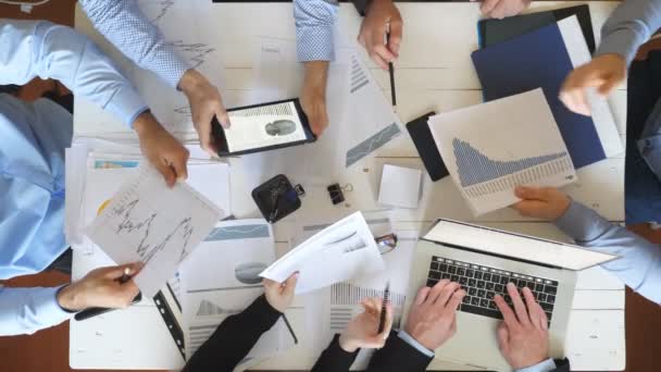 Top view male and female hands of business people planning strategy for corporate project in office. Business team sitting at table and checking financial graphs. Coworkers examining documents at desk - Metraje, vídeo