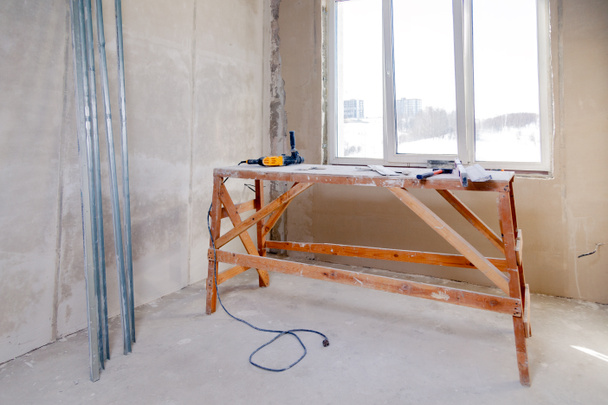 Дерев'яна підставка для риштування біля вікна у великій порожній кімнаті, re
 - Фото, зображення