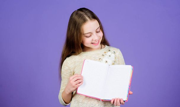 Girl hold book violet background. Kid show book notepad. Book concept. Childhood literature. Development and education. Reading skill. Personal diary. Notepad planner. School stationery. Learn more - Foto, Bild