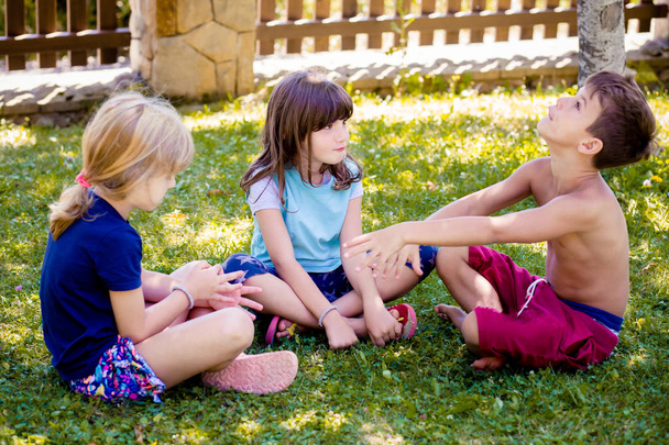 Duas meninas, irmãs e seu amigo menino, se divertindo, brincando no quintal
 - Foto, Imagem